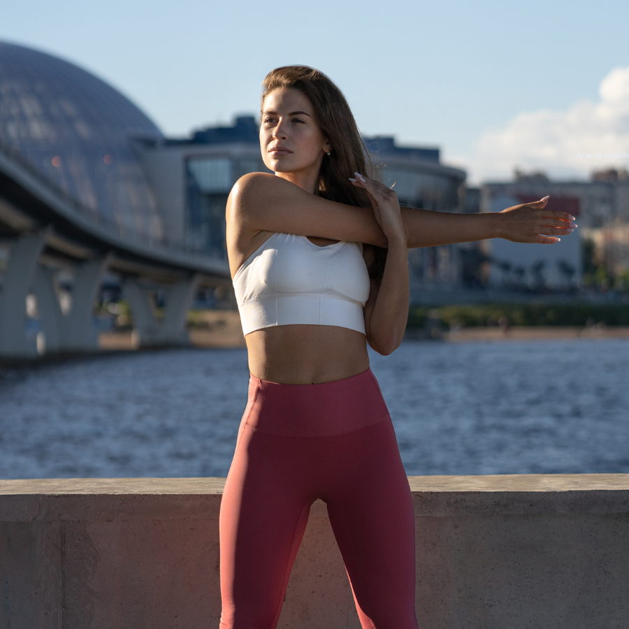 Woman stretching shoulder by the waterfront