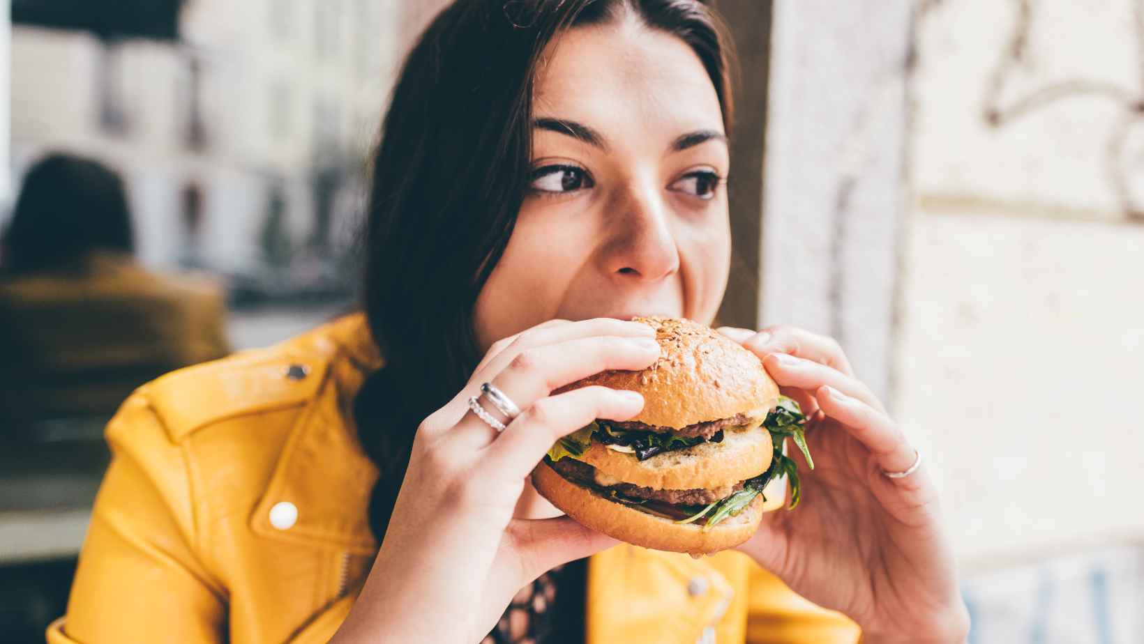 Woman opening mouth wide to eat a burger
