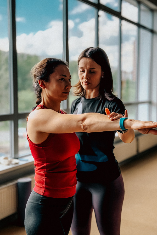 Kinesiologist assess movement of shoulder with  patient in the gym