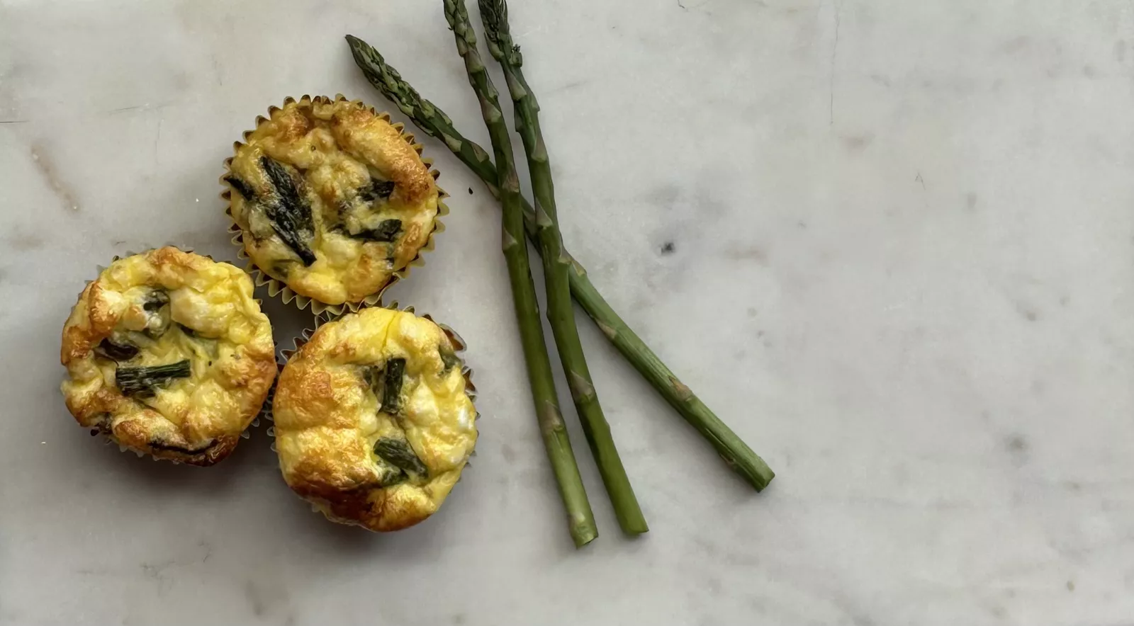 Trio of egg and asparagus tarts on the counter
