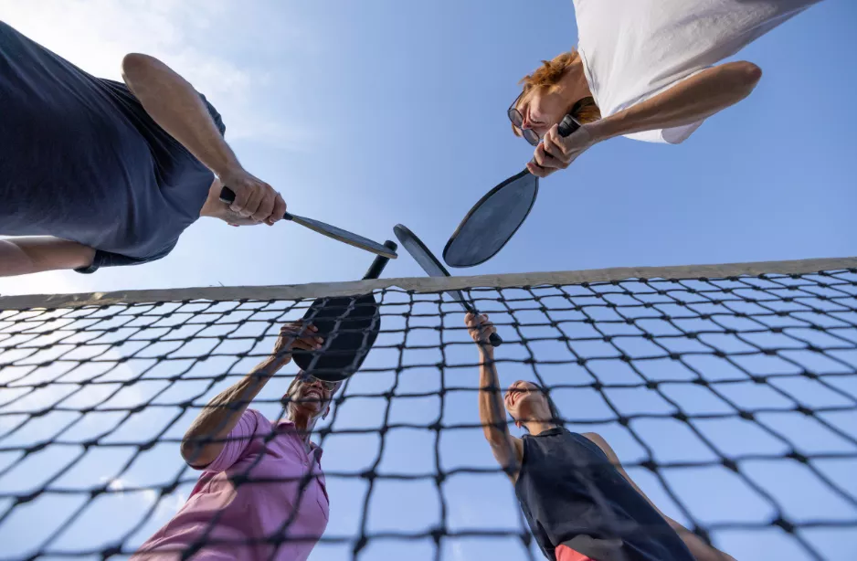 Pickleball players touching raquettes at the net
