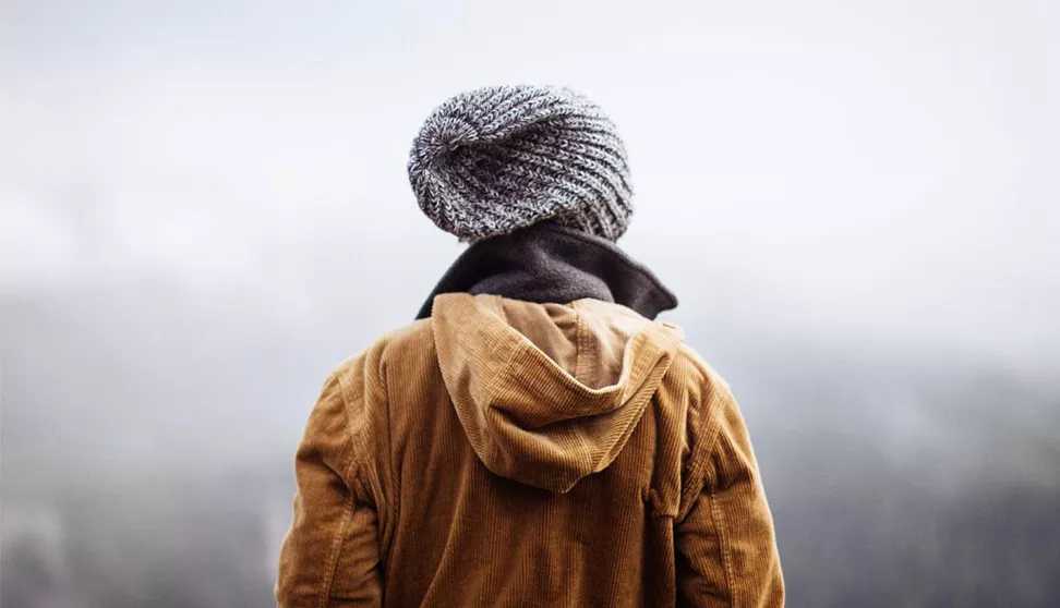 woman standing at a high elevation looking into the clouds