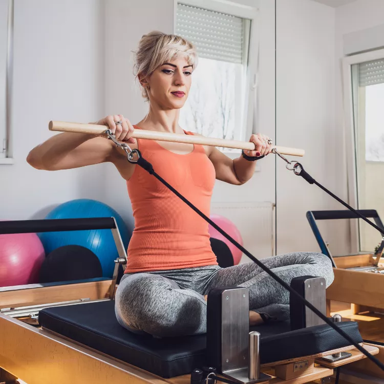 Woman using a pilates reformer to strengthen back and shouders