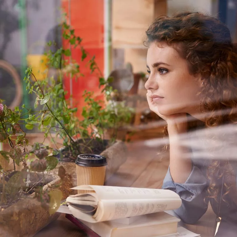 Person deep in thought looking through a window